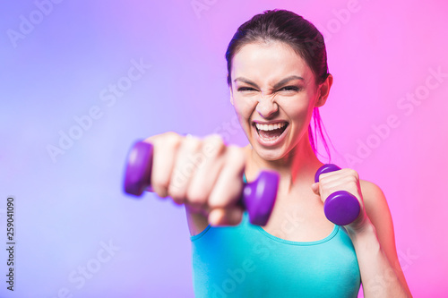 Close-up portrait of young attractive happy woman in sport clothes with beautiful smile holding weight dumbbell doing fitness workout isolated on white background in healthy lifestyle concept