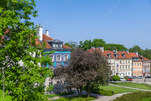 Early color houses surrounded by green trees. Warsaw