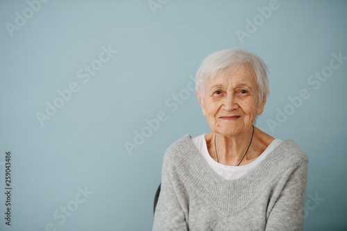 Portrait of elderely grey haired woman in a comfortable sweater at home