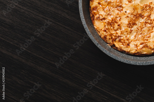 tortilla de patatas on dark wood background, typical spanish dish. Copy space for text and top view