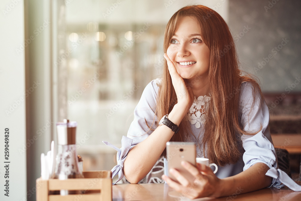 Young business woman using her smart phone and smiling in coffee shop Young business woman using her smart phone and smiling in coffee shop