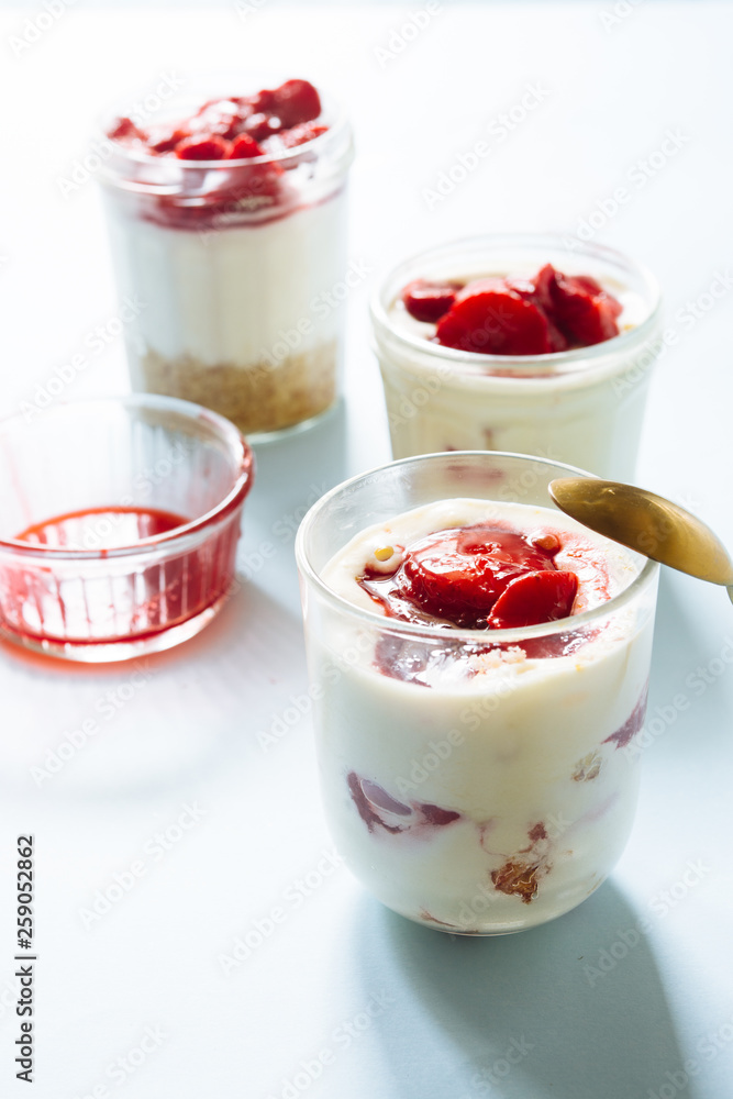 Tiramisu with strawberry in glass on a blue board, natural backlight Tiramisu with strawberry in glass on a blue board, natural backlight