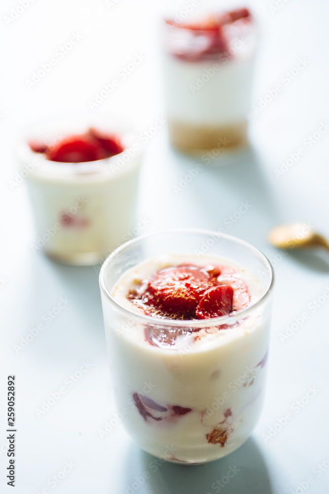 Tiramisu with strawberry in glass on a blue board, natural backlight Tiramisu with strawberry in glass on a blue board, natural backlight