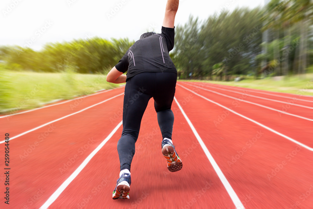 portrait of young male athlete running on running track (back view)