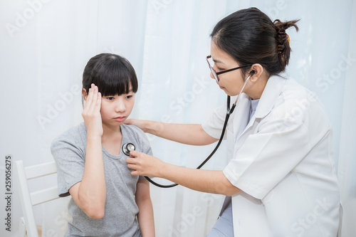 Young asian girl at the doctor's clinic. Asian doctor woman examining teenage girl with stethoscope pediatric checkup. Healthcare and medical sickness stressful concept