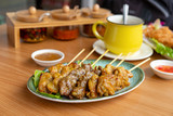 Six pieces of satay on a wood table