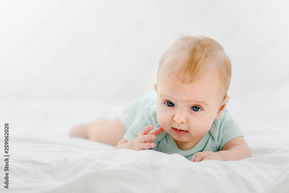 Portrait of beautiful infant baby lying on stomach in bed Portrait of beautiful infant baby lying on stomach in bed