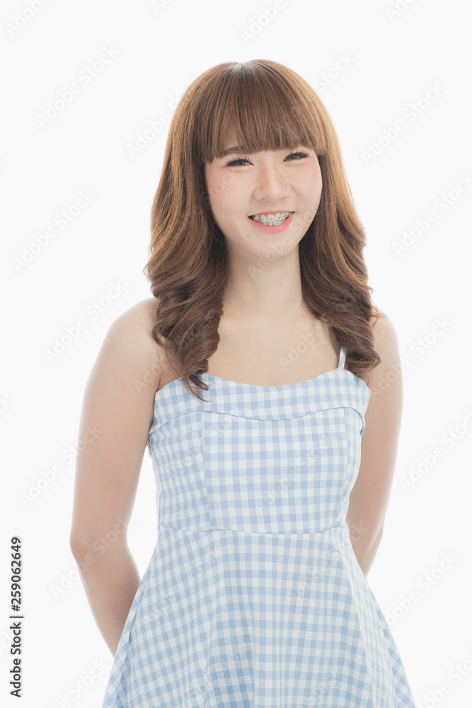 Front view close-up portrait of young beautiful Asian woman with curly long dark brown hair in light blue checked dress stand up straight isolated white background Front view close-up portrait of young beautiful Asian woman with curly long dark brown hair in light blue checked dress stand up straight isolated white background