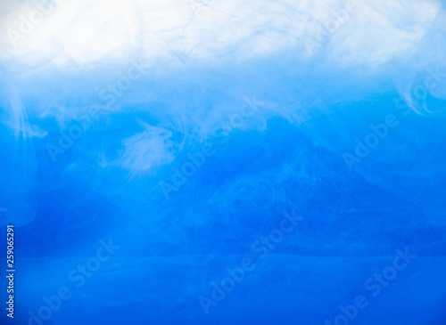 Ink in water, close up. Abstract background. Blue paint dissolving into water. Abstract acrylic clouds in liquid. Waves of acrylic ink in water. Abstract pattern of paint. Blurred background