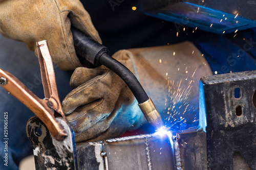 A mig welder is used to weld two pieces of metal steel together close up