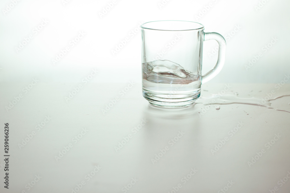 Water wave in transparent glass and puddle on gray background. purified fresh drink water on table Water wave in transparent glass and puddle on gray background. purified fresh drink water on table