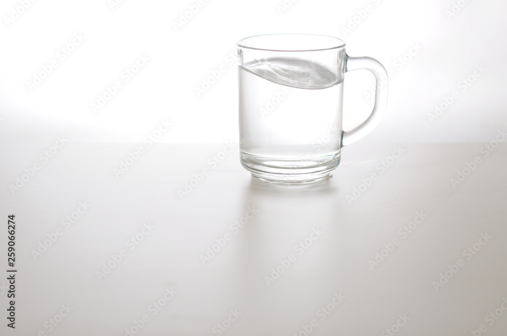 Water wave in transparent glass and puddle on gray background. purified fresh drink water on table Water wave in transparent glass and puddle on gray background. purified fresh drink water on table