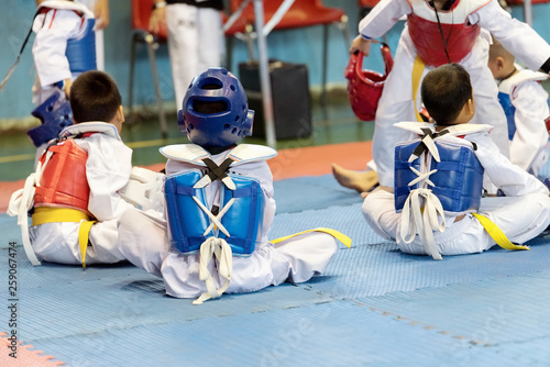 Taekwondo Kids action with uniform sitting and listen to martial training.