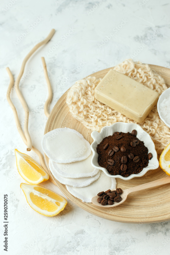 Fototapeta premium Ingredients for prepare homemade coffee scrub. Coffee grains, sea salt, soap, lemon on wooden plate and gray background, wellness homemade stylish organic concept