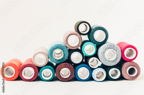 Colored sewing thread coils on white background with copy space for text.