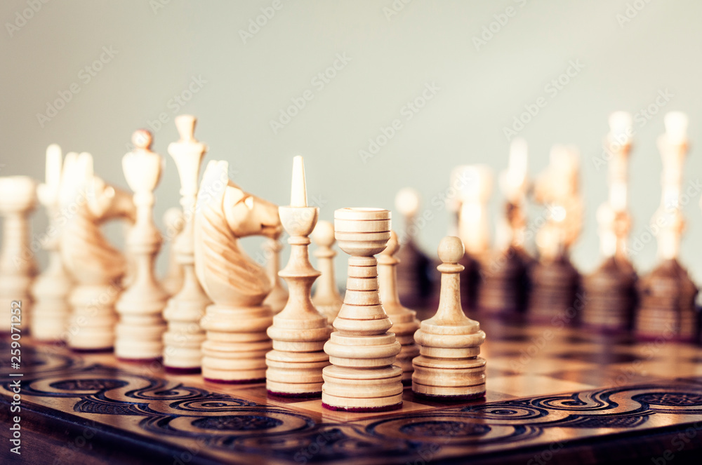 Wooden chess pieces on a chessboard, leadership concept on white background.