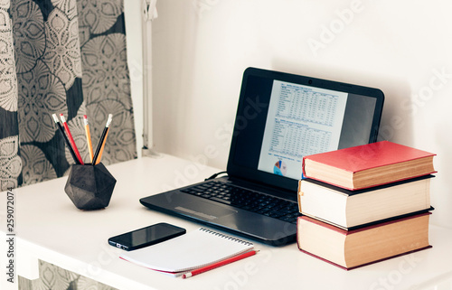 laptop, stack of books, notebook, smartphone in office background for education learning concept.