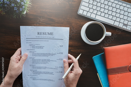 New graduate student holding resume application with pen coffee cup keyboard and notebook for applying for a job.