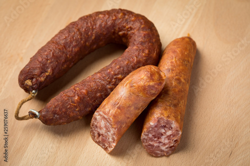 Luftgetrockneter Mettwurst Ring und frische Bierbeißer, zwei Salami Sorten aus Schweinefleisch auf Holz Brett 