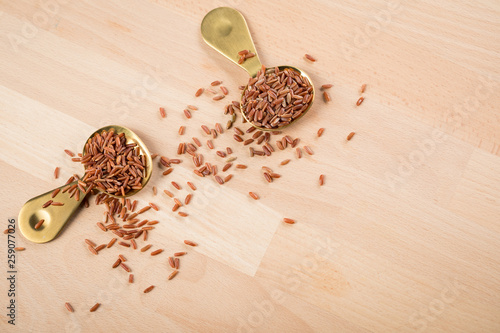 Rotschaliger roher roter Reis aus Piemont Italien und roter Jasmin Reis aus Kambodscha Asien in Metall Löffel auf Holz Hintergrund photo