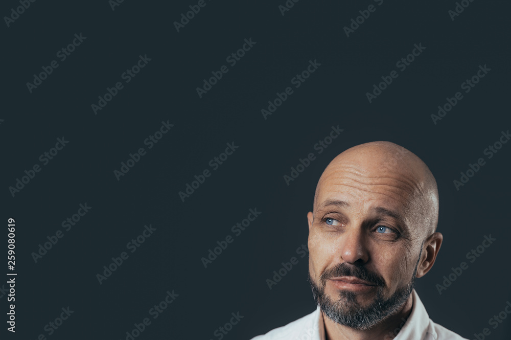 Serious middle-aged man with a smile dressed in casual poses on a dark gray background Serious middle-aged man with a smile dressed in casual poses on a dark gray background
