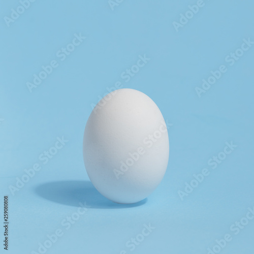 White chicken egg on a blue background. Preparation for coloring of Easter egg. Easter holiday concept.