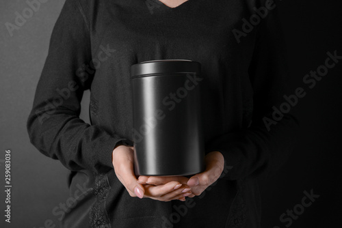 Woman with mortuary urn on dark background, closeup photo