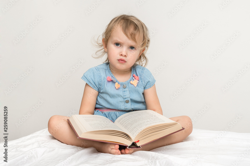 Cute little child in blue dress reading a book Cute little child in blue dress reading a book