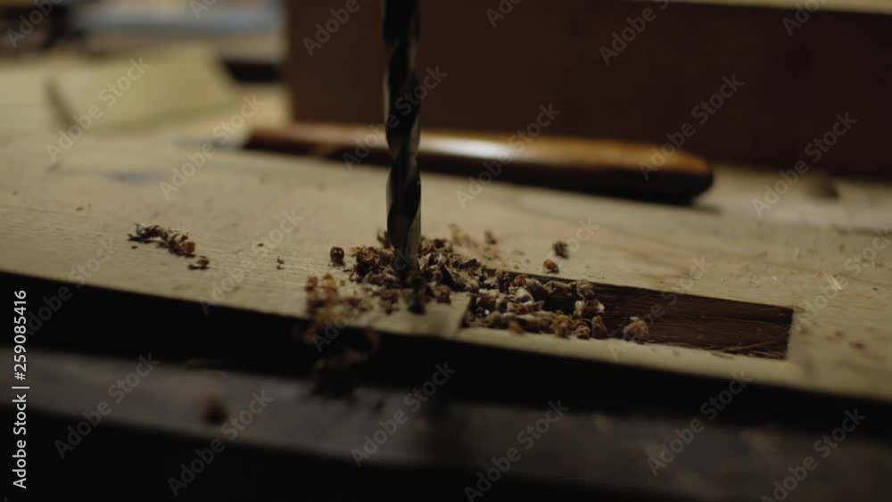 metal drill makes a hole in the wooden detail.backlit drill.close-up.4k metal drill makes a hole in the wooden detail.backlit drill.close-up.4k