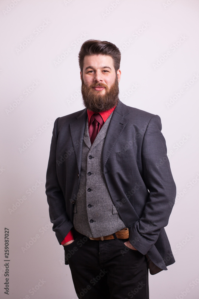 Cool young bearded man in grey business suit looking at the camera over white background Cool young bearded man in grey business suit looking at the camera over white background