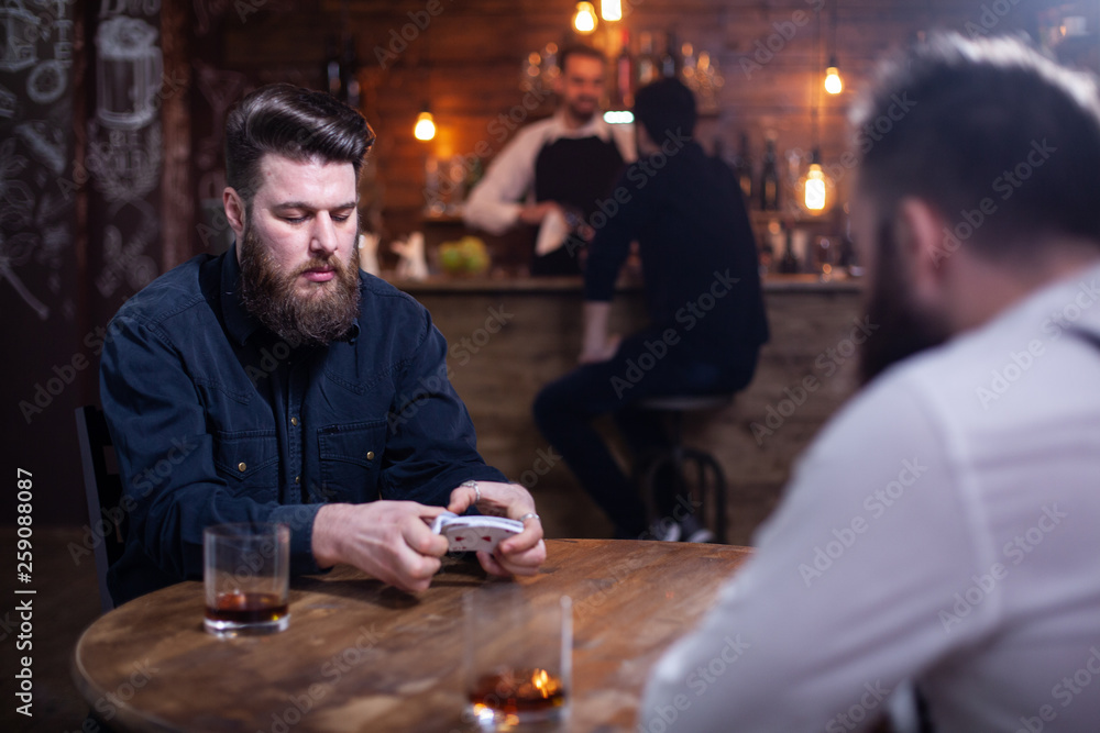 Two bearded hipsters playing a card game in a pub
