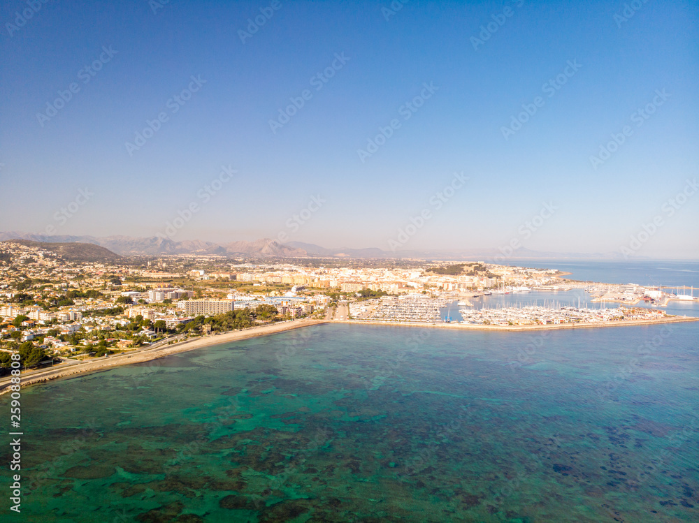 marineta 04Aerial view of Denia city in Spain on a sunny day. Marineta Beach is in the foreground. Some mountains in the background