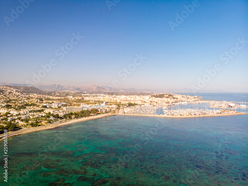 marineta 04Aerial view of Denia city in Spain on a sunny day. Marineta Beach is in the foreground. Some mountains in the background