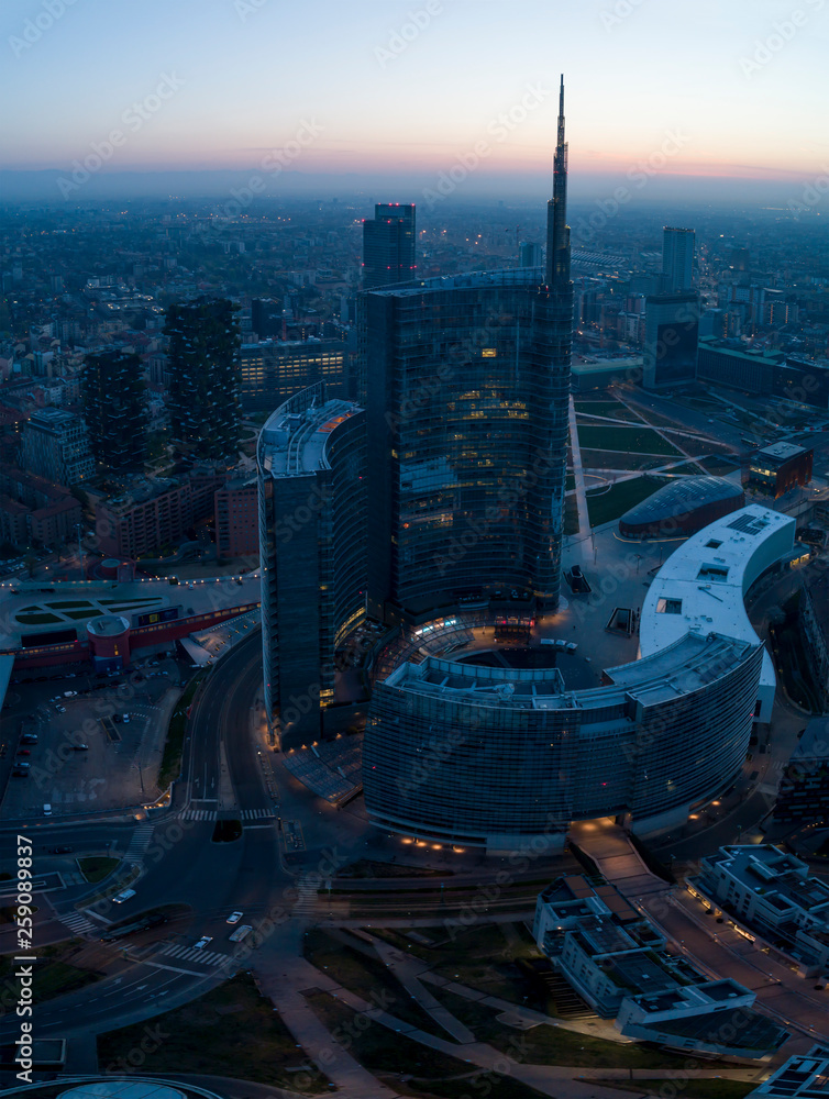 Fototapeta premium Mediolan (Włochy) panoramę miasta o świcie, widok z lotu ptaka, latające nad wieżowcami obszaru finansowego w dzielnicy Porta Nuova. Budynek biurowy Unicredit Tower o wschodzie słońca.