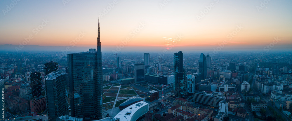 Naklejka premium Mediolan (Włochy) panoramę miasta o świcie, widok z lotu ptaka, latające nad wieżowcami obszaru finansowego w dzielnicy Porta Nuova. Budynek biurowy Unicredit Tower o wschodzie słońca.