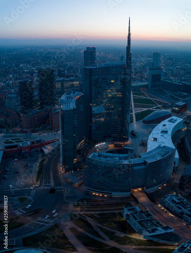 Milan (Italy) city skyline at dawn, aerial view, flying over financial area skyscrapers in Porta Nuova district. Unicredit Tower office building at sunrise. photo