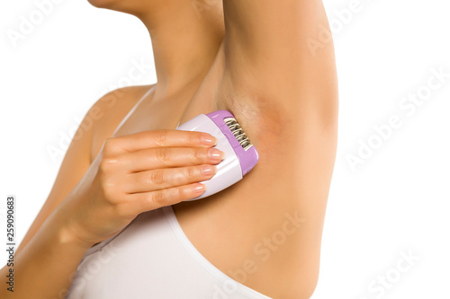 woman remove her underarm hair with electric epilator on white background © vladimirfloyd