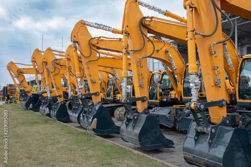 Lots of yellow tractors or excavators at an exhibition