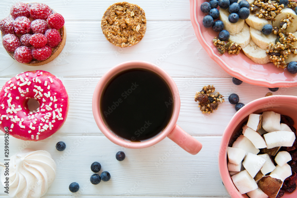 Different kinds of sweets and a cup of coffee on white wooden table background. Top view. Different kinds of sweets and a cup of coffee on white wooden table background. Top view.