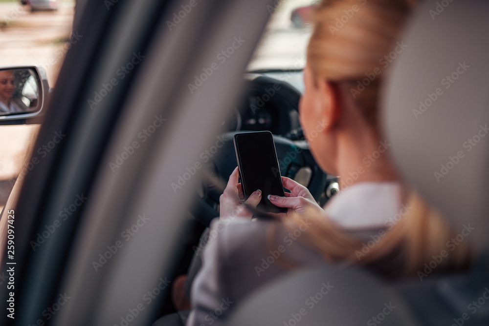 Using phone while sitting in driver seat in the car, close-up. Using phone while sitting in driver seat in the car, close-up.