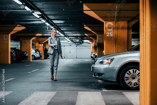 Fotografie, Obraz Successful businesswoman walking to her car in underground car parking