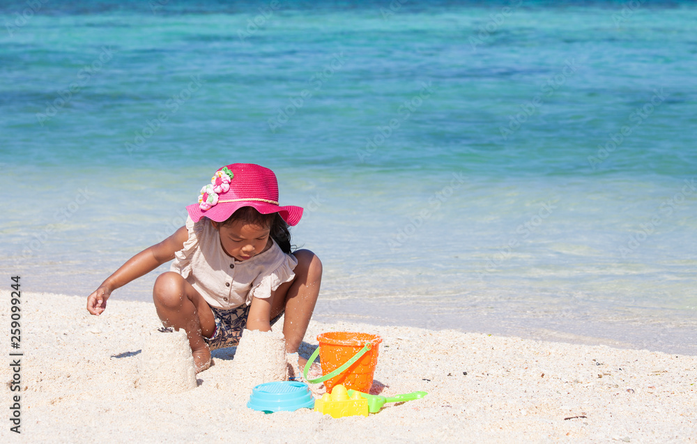 Cute asian child girl having fun to play with sand on beach in summer vacation Cute asian child girl having fun to play with sand on beach in summer vacation