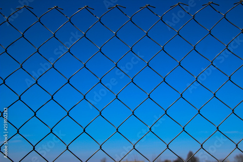 Metal mesh fence against a blue sky