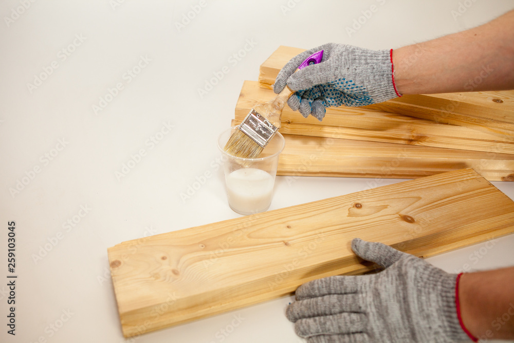 The man handles the Board primer. Processing of pine boards, biosecurity, fire protection. Technology and production. Men's gloved hands