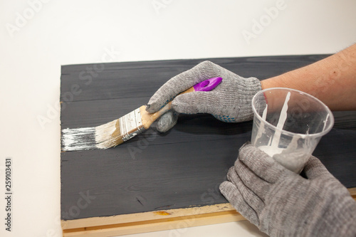 Master paints the Board with white paint. Create fotofone for advertising from wood. Toning the Board with white paint. White paint on black paint.