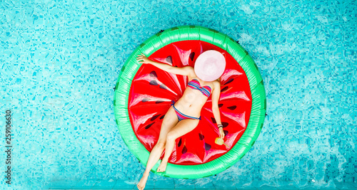 Canvas-taulu Young woman relaxing on watermelon lilo in villa resort pool
