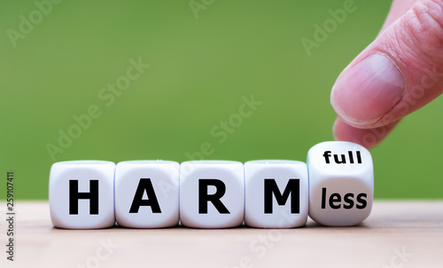 Bild auf Leinwand Hand turns a dice and changes the expression harmful to harmless