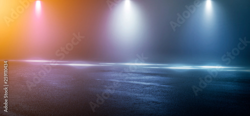 Wet asphalt  reflection of neon lights  a searchlight  smoke. Abstract light in a dark empty street with smoke  smog. Dark background scene of empty street  night view  night city.