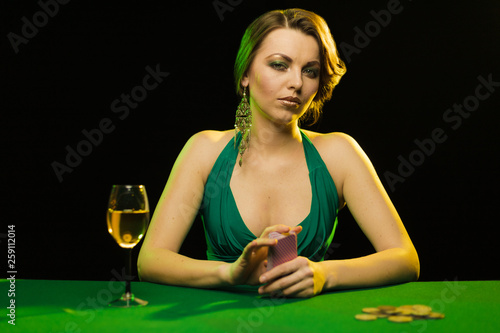 A young lady in a green dress is playing solitaire made from scrying cards on a table on a green card cloth. photo