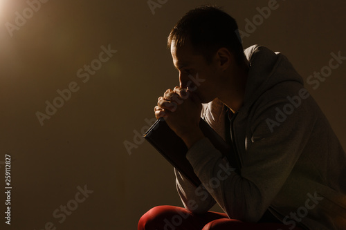 Religious young man praying to God on dark background, black and white effect